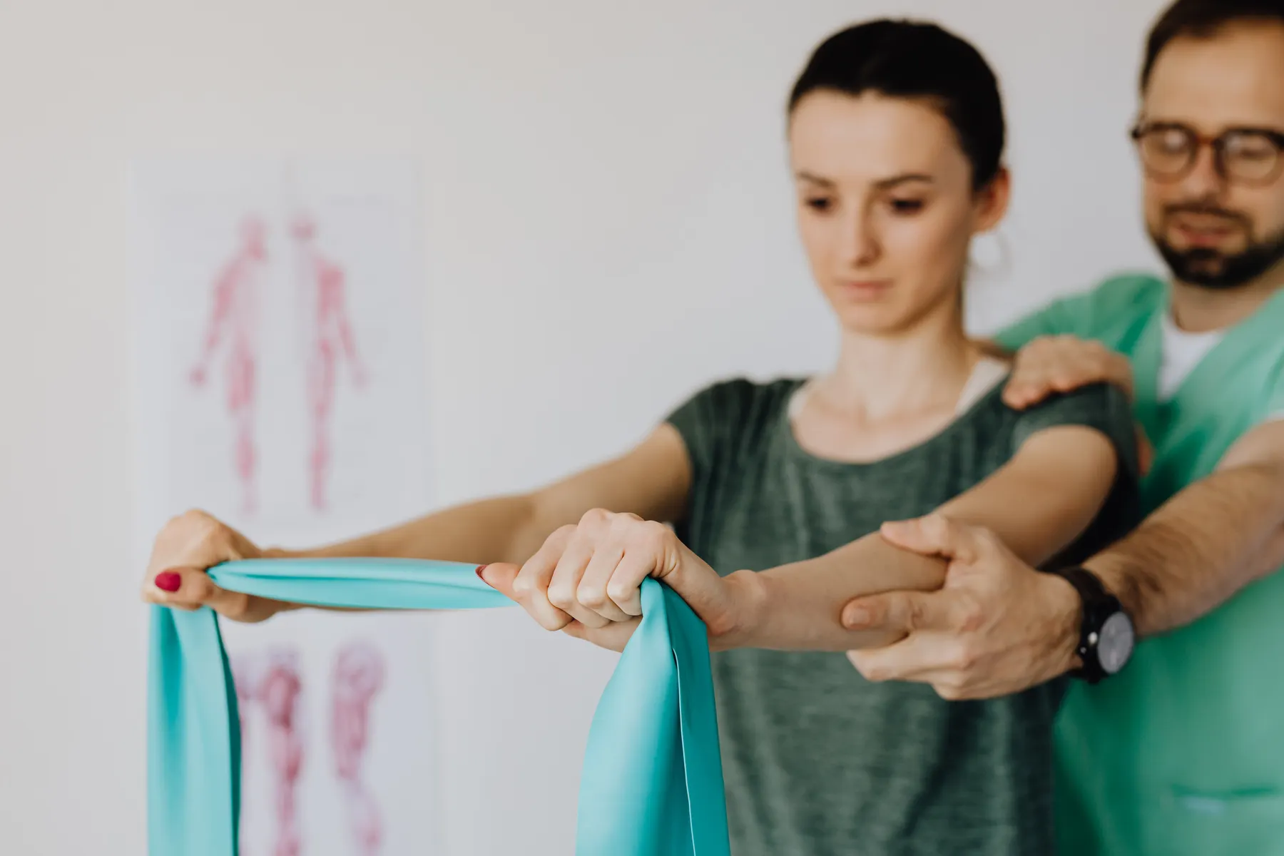 Fisioterapeuta corrigiendo el movimiento del hombro de una paciente durante un ejercicio con banda elástica