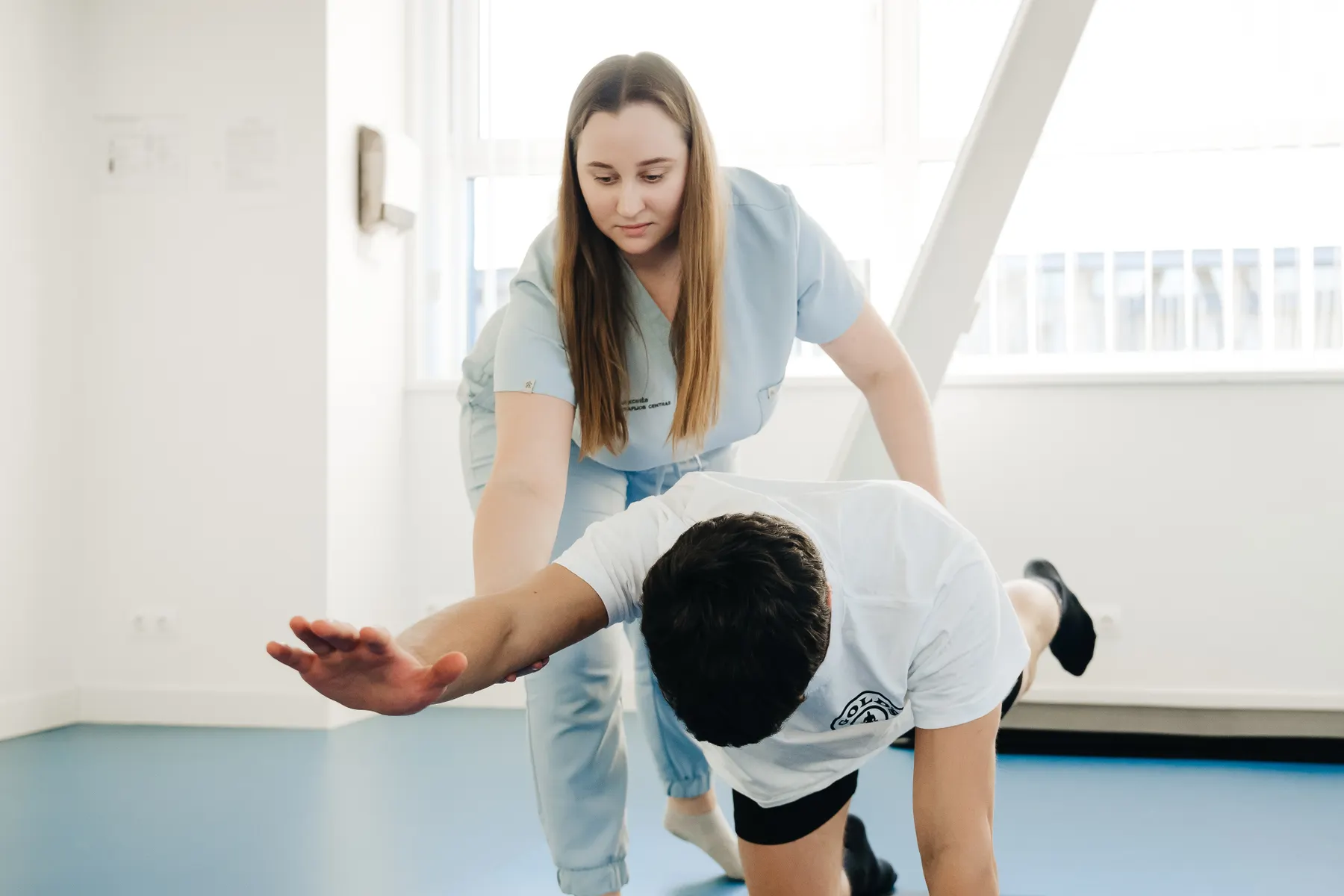 Fisioterapeuta guiando a un paciente en un ejercicio de estabilidad en la sala de ejercicio